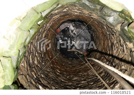 A man in the middle of a well cleans the bottom of dirt and accumulated silt. A man in the middle of a well cleans the bottom of dirt and accumulated silt. 116018521