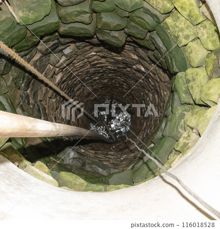 The village well is paved with stone, a view of the well in the middle. 116018528
