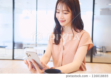 一位女士在辦公室食品儲藏室裡看著她的智慧型手機 116018693