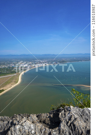 A view of the sparkling blue ocean from a sandy beach, with a clear sky overhead 116018987