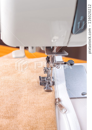 Modern sewing machine special presser foot with beige velveteen fabric and zipper, closeup Modern sewing machine special presser foot with beige velveteen fabric and zipper, closeup 116020212