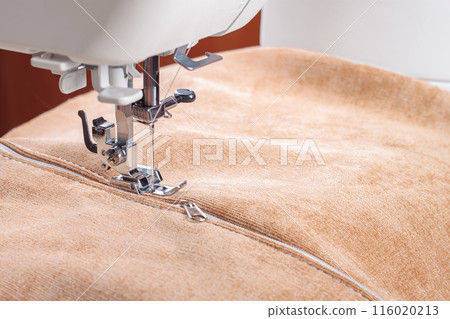 Modern sewing machine special presser foot with beige fabric and zipper, closeup Modern sewing machine special presser foot with beige fabric and zipper, closeup 116020213