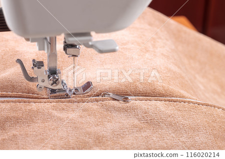Modern sewing machine special presser foot with beige velveteen fabric and zipper, closeup 116020214