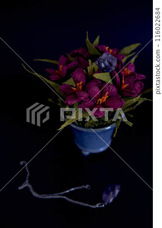 amethyst ring and a pendant of paper flowers in a blue vase on a black background amethyst ring and a pendant of paper flowers in a blue vase on a black background 116022684