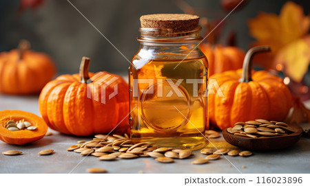 Bottle pumpkin oil surrounded whole pumpkins and pumpkin seeds placed on wooden surface 116023896