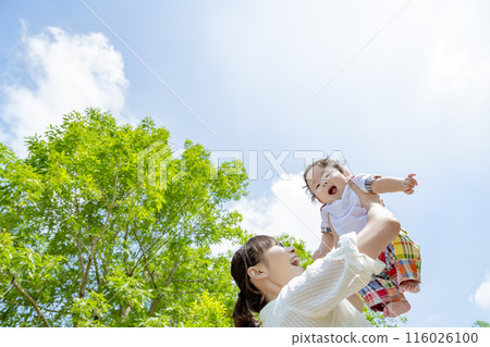 Mother holding her toddler up in the park 116026100