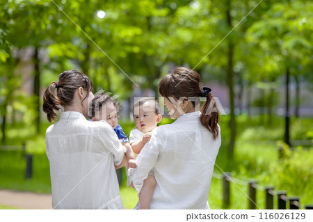 兩組家長和孩子抱著一個幼兒在公園聊天 116026129