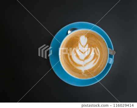 A beautifully crafted latte with delicate foam art in a blue cup on a dark background A beautifully crafted latte with delicate foam art in a blue cup on a dark background 116029414