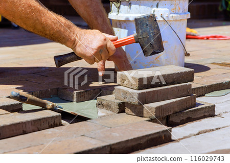 Employee is repairing footpath by replacing damaged bricks during reconstruction Employee is repairing footpath by replacing damaged bricks during reconstruction 116029743
