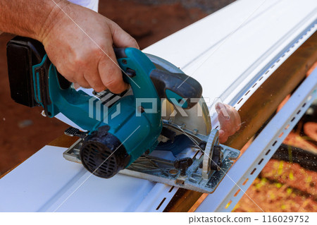 Craftsman cuts vinyl siding panels to their desired size during construction Craftsman cuts vinyl siding panels to their desired size during construction 116029752