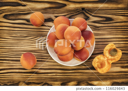 On the table and on a white saucer lie ripe apricots On the table and on a white saucer lie ripe apricots 116029843
