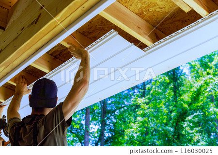 Having new employee install vinyl soffit plastic panels on facade ceiling of new house Having new employee install vinyl soffit plastic panels on facade ceiling of new house 116030025
