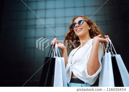 Woman in shopping. Woman with shopping bags walking around city after shopping. Lifestyle concept. Woman in shopping. Woman with shopping bags walking around city after shopping. Lifestyle concept. 116030454