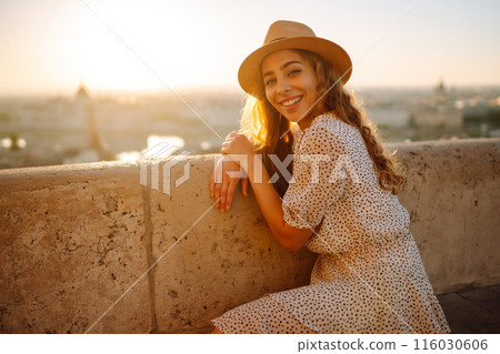 Portrait of happy tourist in hat at dawn enjoys cityscape. Traveling in Europe. Concept tourism. Portrait of happy tourist in hat at dawn enjoys cityscape. Traveling in Europe. Concept tourism. 116030606