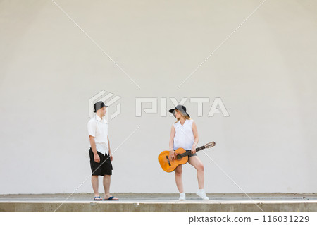 Woman playing guitar, man standing next to her 116031229
