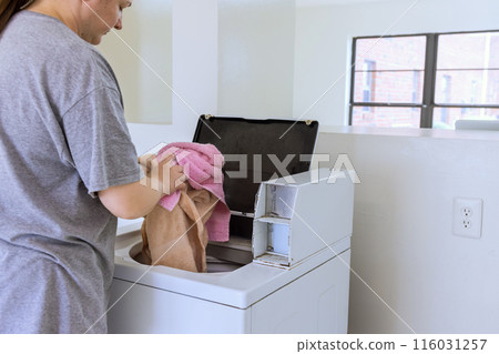 An employee of laundromat washes towels in washing machine An employee of laundromat washes towels in washing machine 116031257