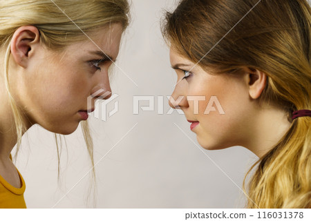 Two girls looking serious at each other. Two girls looking serious at each other. 116031378