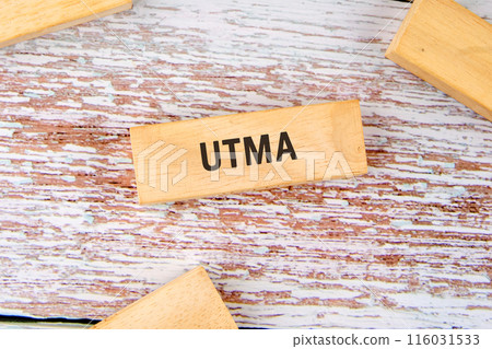 Business concept. UTMA word on wooden blocks on old boards Business concept. UTMA word on wooden blocks on old boards 116031533