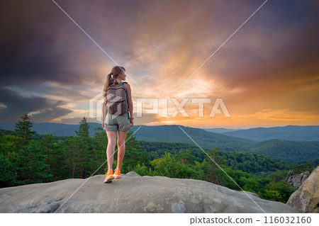 Young woman hiker standing alone on mountain footpath enjoying view of evening nature on wilderness trail. Active way of life concept 116032160