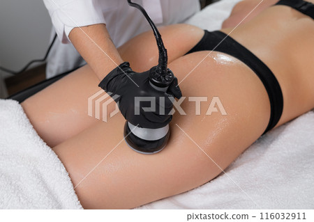 Young woman undergoes body contouring of buttocks via ultrasound cavitation. 116032911