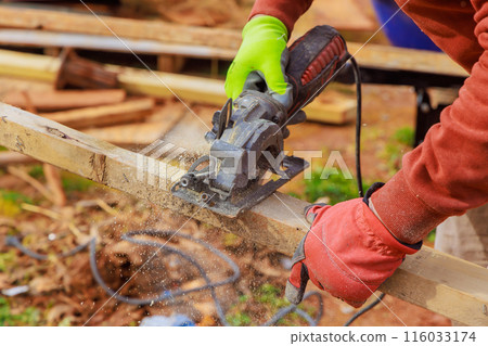 Carpenter hands working on cutting wooden beam with hand saw 116033174