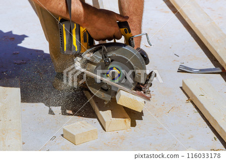 Woodworking carpenter cutting wooden beams with handsaw 116033178