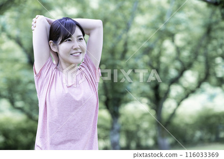 一個女人在新鮮的綠色植物中伸展身體 116033369