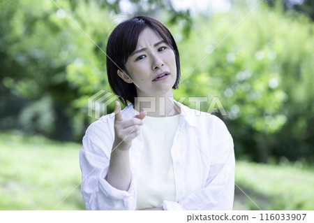 Dissatisfied woman in a park with fresh green leaves 116033907