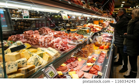In the deli section, arranged meats and cheeses attract shoppers eager to sample the offerings. 116034245