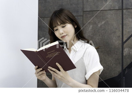 Young woman reading a book on the stairs Young woman reading a book on the stairs 116034478