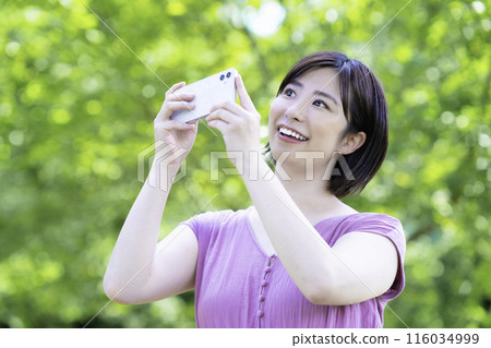 一位女士用智慧型手機在新鮮的綠色植物中拍照 一位女士用智慧型手機在新鮮的綠色植物中拍照 116034999