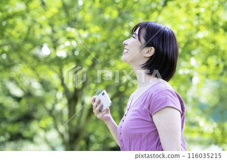 A woman taking a smartphone photo in the fresh greenery 116035215