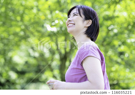 A woman taking a smartphone photo in the fresh greenery 116035221