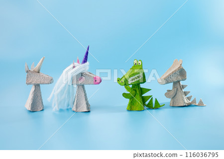Crafted toy animals standing next to each other: unicorn, alligator, miniature figurine. Several character designs in a fairy tale scene featuring finger toys made from recycled materials, DIY 116036795
