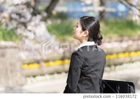 A young businesswoman looking at the cherry blossoms along a tree-lined river A young businesswoman looking at the cherry blossoms along a tree-lined river 116038172