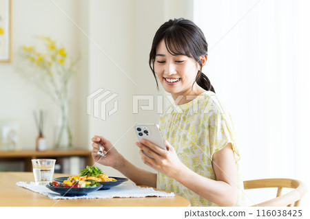 年輕女子在家吃義大利麵時看著智慧型手機 116038425
