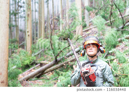 一名林業工人拿著電鋸，目光略高於上方，背景是正在工作的山林 116038448