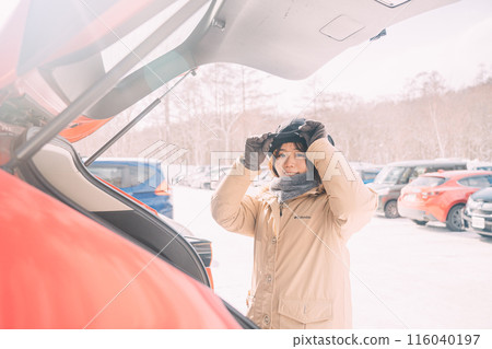 A woman who opens a trunk of a car A woman who opens a trunk of a car 116040197