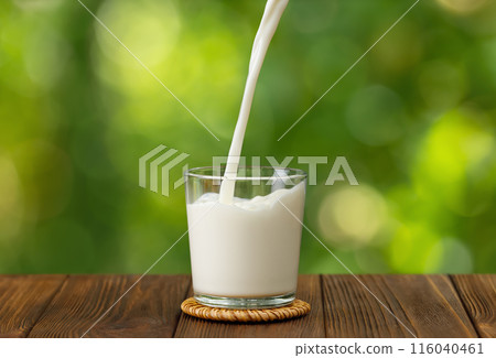 milk pouring into glass on wooden table milk pouring into glass on wooden table 116040461