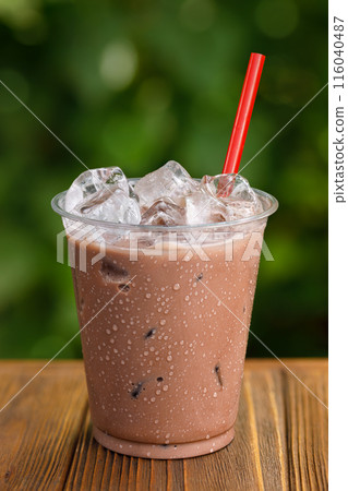 disposable glass of chocolate milkshake with ice on wooden table disposable glass of chocolate milkshake with ice on wooden table 116040487