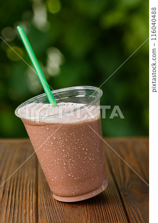 tilted plastic glass of chocolate milkshake on wooden table tilted plastic glass of chocolate milkshake on wooden table 116040488