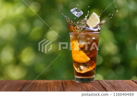 glass of iced tea with splash and falling slice of lemon on wooden table glass of iced tea with splash and falling slice of lemon on wooden table 116040489