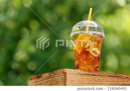 iced tea with lemon in disposable plastic glass on wooden table iced tea with lemon in disposable plastic glass on wooden table 116040491