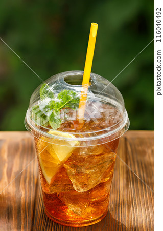 iced tea with lemon in disposable plastic glass on wooden table iced tea with lemon in disposable plastic glass on wooden table 116040492