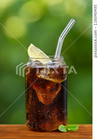 glass of cold cola with ice cubes or cuba libre cocktail on wooden table outdoors 116040495