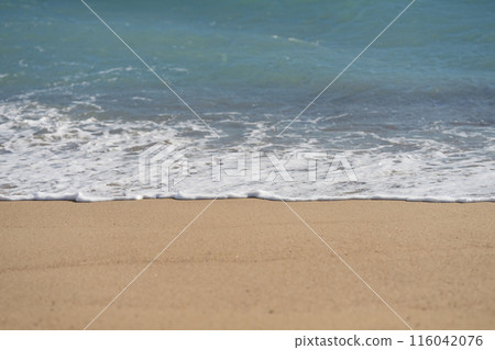 Waves rolling on a sandy beach on a sunny day 116042076