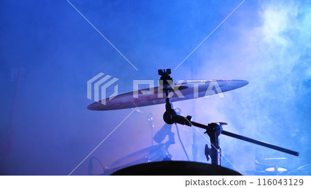 A drum set takes center stage, bathed in blue lights, ready for a rhythmic performance in a music venue. 116043129