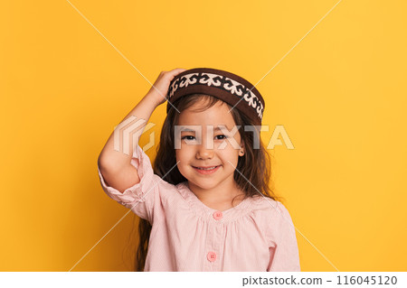 Child in a Kazakh skullcap in front of a yellow background Child in a Kazakh skullcap in front of a yellow background 116045120
