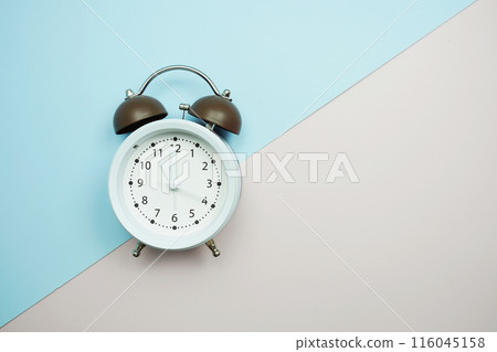 Top view of alarm clock with space copy flat lay on blue and pink background 116045158