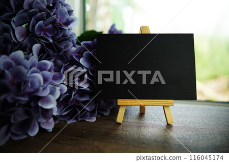 Empty card space for text message with wooden easel and flower bouquet on wooden background Empty card space for text message with wooden easel and flower bouquet on wooden background 116045174